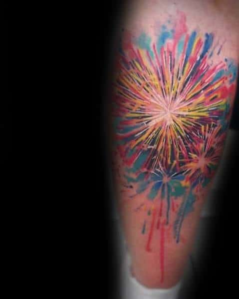 Watercolor-style tattoo of vibrant fireworks bursting in shades of yellow, red, and blue, with dripping ink for a dynamic and artistic effect.