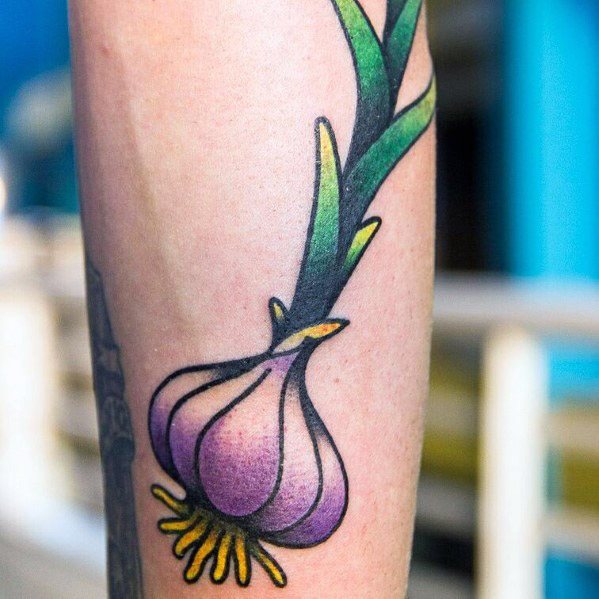 Colorful garlic tattoo with bold outlines, vibrant purple shading, and green leaves, creating a striking and lively botanical design.