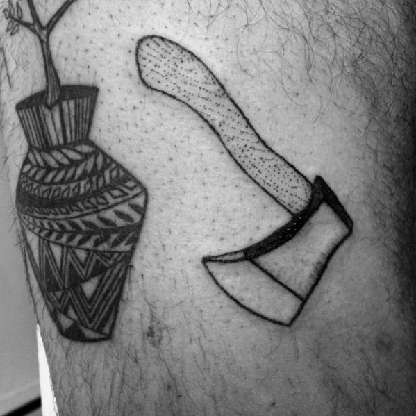 Minimalist hatchet tattoo with a dotted shading technique on the handle and a simple outlined blade, placed near a geometric-patterned vase tattoo.