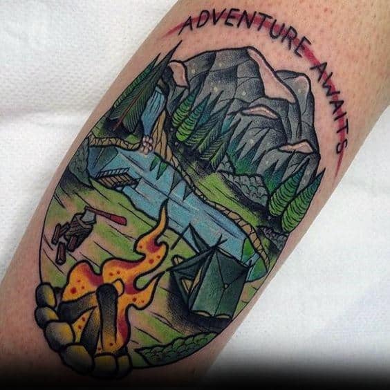 This vibrant tattoo captures adventure with a campfire, tent, river, and mountains, topped with "ADVENTURE AWAITS" for a bold touch.