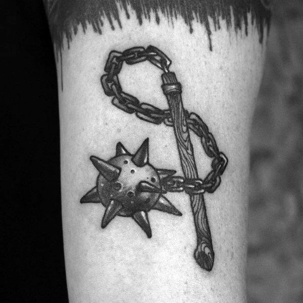 Black and gray mace tattoo featuring a spiked ball on a chain with a detailed wooden handle, symbolizing strength, power, and medieval warfare.