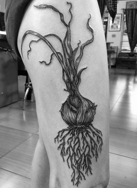 Black and grey onion tattoo on the thigh, featuring intricate roots and long, flowing sprouts with fine line details for a natural, botanical look.