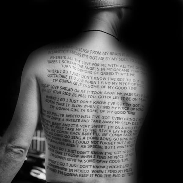 Full back tattoo featuring song lyrics in bold black lettering, creating a striking text-based design inspired by Red Hot Chili Peppers.