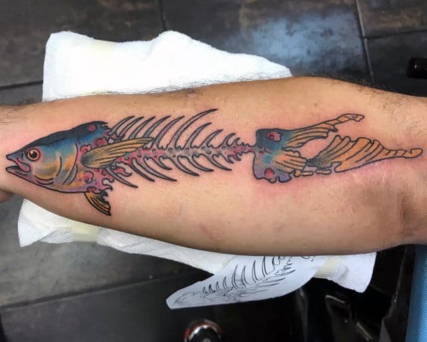 Tattoo of a tuna fish skeleton on a man's forearm, featuring bold outlines, vibrant colors, and intricate shading for a striking design.