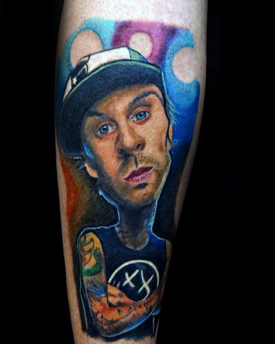 Colorful and detailed tattoo of Travis Barker with a Blink-182 logo on his shirt, featuring a stylized, vibrant background and intricate shading to capture his likeness.