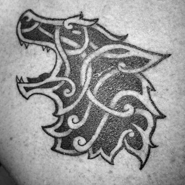 Roaring Celtic wolf head tattoo with bold black fill and swirling knotwork lines forming a fierce and stylized silhouette.