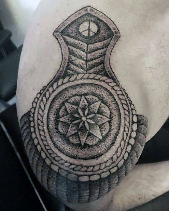Epaulette tattoo with a detailed dotwork mandala centerpiece, rope-like border, and bold shoulder padding design.