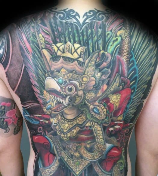 Full back Garuda tattoo in vibrant colors featuring a richly adorned winged deity with detailed feathers, armor, and dynamic background.