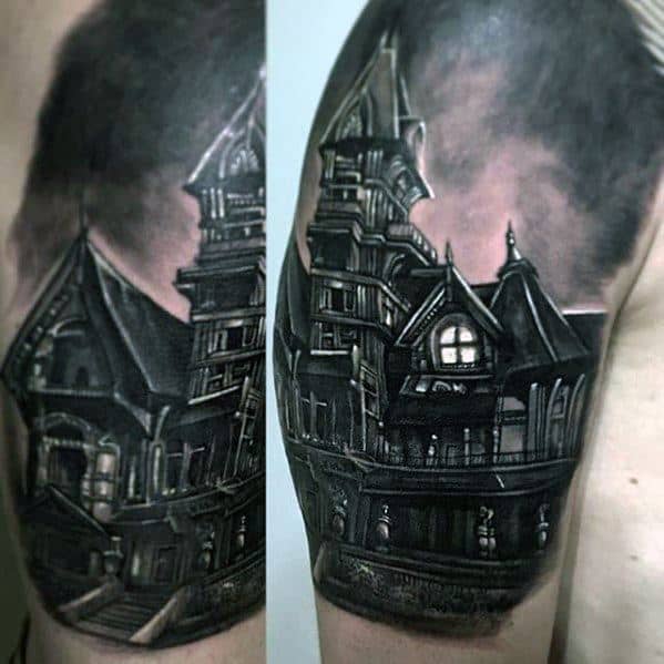 Upper arm tattoo of a large haunted mansion with gothic windows, dramatic shadows, and a cloudy, ominous sky in a realistic style.