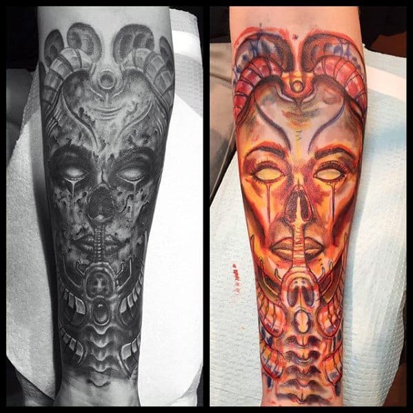 Forearm tattoo inspired by HR Giger, featuring a biomechanical female face—shown in both black and grey and vibrant red-orange color styles.