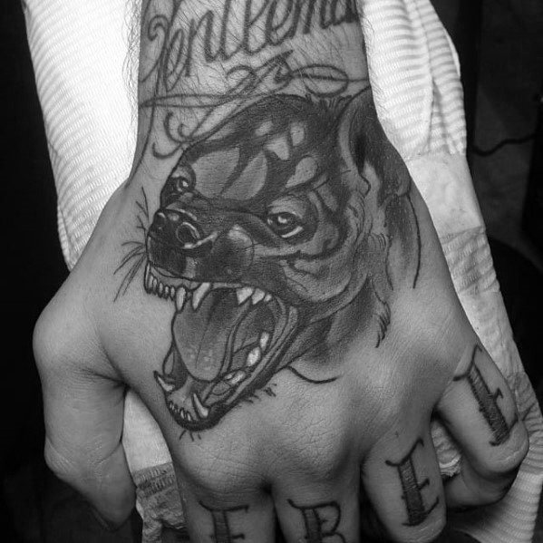 Black and grey hyena tattoo on the hand featuring a snarling expression with detailed shading, open jaws, and bold linework.