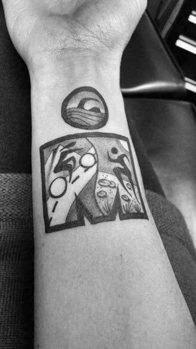 Ironman logo tattoo with black and white illustrations of a wave, cyclist, swimmer, and runner, representing the triathlon disciplines.