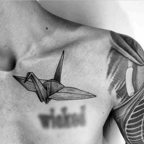 Minimalist chest tattoo of an origami crane, done in clean black lines, symbolizing peace, transformation, and refined simplicity.