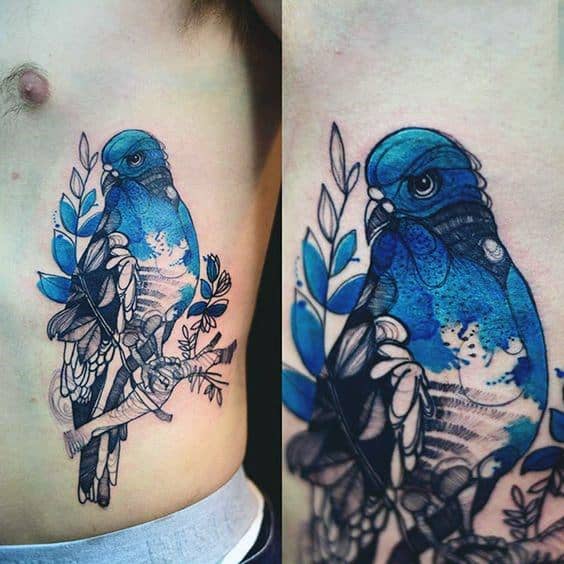 Vibrant blue pigeon tattoo on side torso with artistic leaf details and bold linework, blending realism with watercolor-style flair.