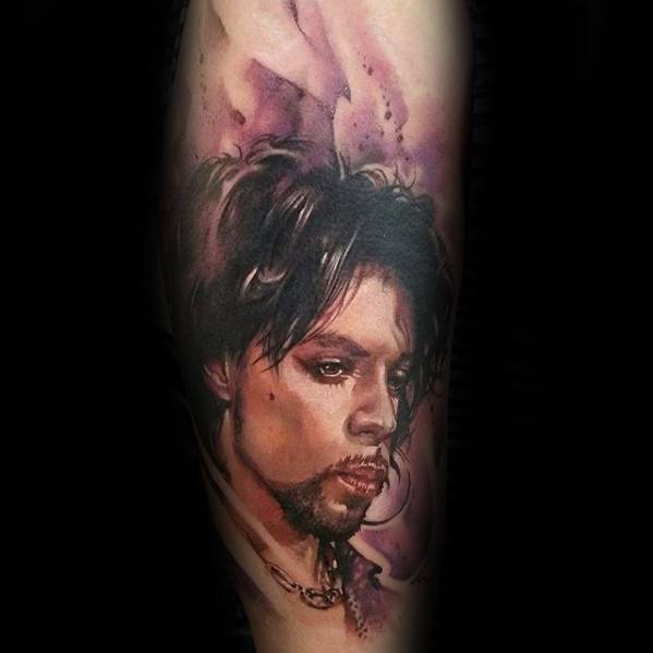 Tattoo of a serious-faced person with dark hair, reminiscent of Prince, against a purple-toned background
