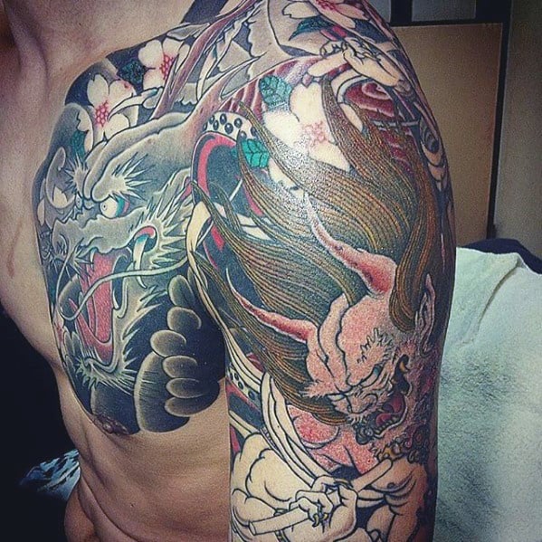 Detailed Raijin shoulder and chest tattoo with fierce thunder god, flowing hair, roaring dragon, and bold traditional Japanese elements.