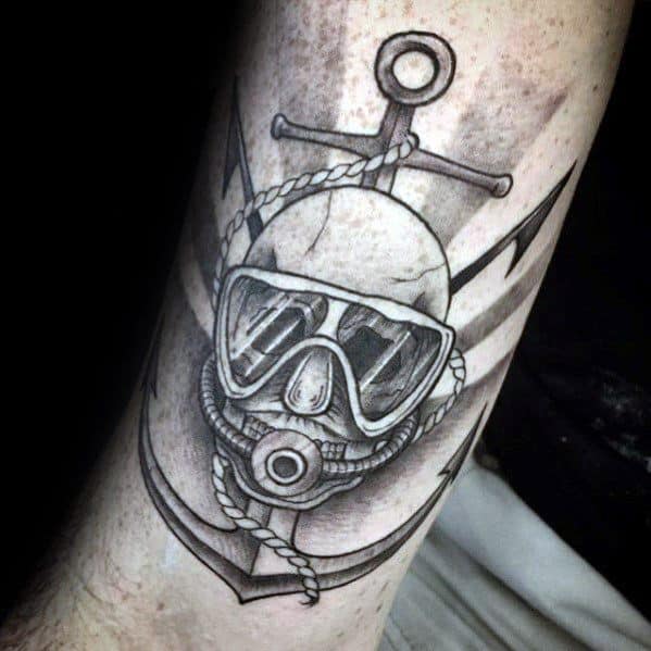 Black and grey tattoo of a scuba skull with diving mask and regulator, set over a large anchor wrapped in rope.