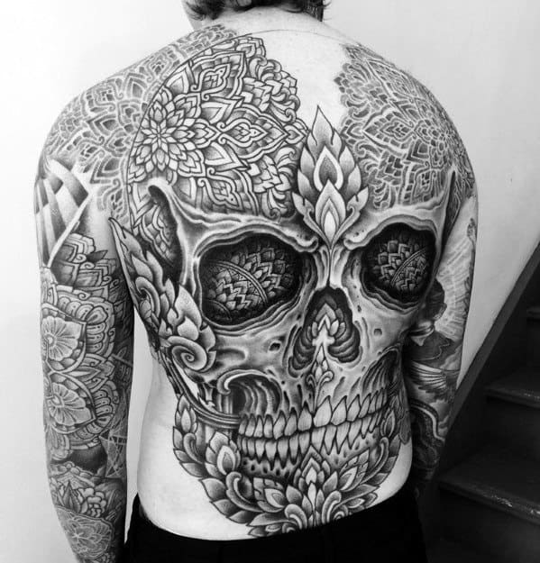 Intricate back tattoo of a skull with detailed patterns in black and gray