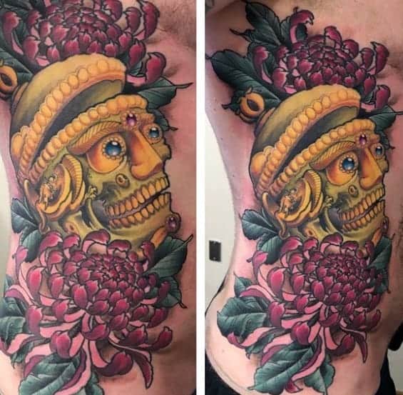 Colorful tattoo of a golden skull with flowers and leaves