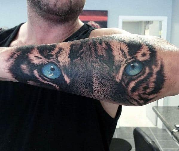 Forearm with a realistic tattoo of a tiger's eyes and surrounding fur