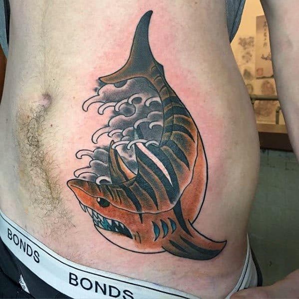 Traditional tiger shark tattoo on the side torso, featuring bold orange and black stripes with crashing wave elements inside the body.