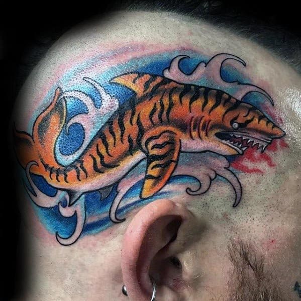 Bold tiger shark tattoo on the scalp with vivid orange stripes, blue waves, and fierce teeth for a daring and eye-catching design.