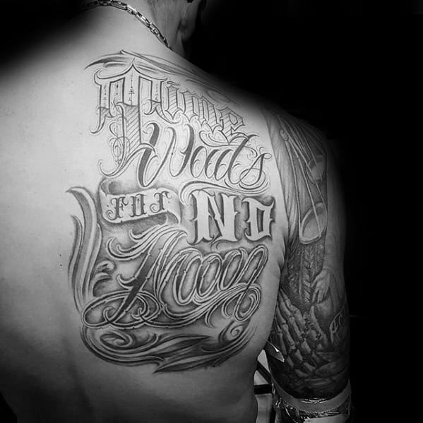 Large back tattoo in stylized script reading Time Waits for No Man, blending bold and cursive lettering styles.