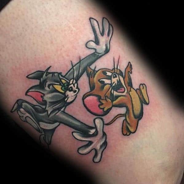Colorful tattoo of Tom lunging to catch a panicked Jerry, showcasing their classic cartoon chase scene on the skin.