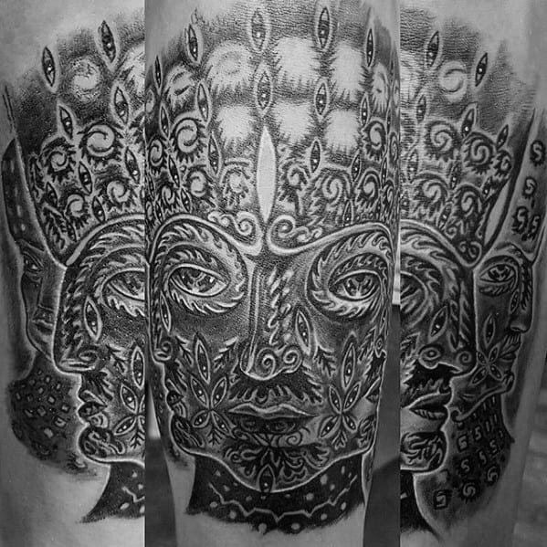Black and grey Tool-inspired tattoo with a multi-faced symmetrical design, intricate patterns, and rows of eye motifs radiating upward.