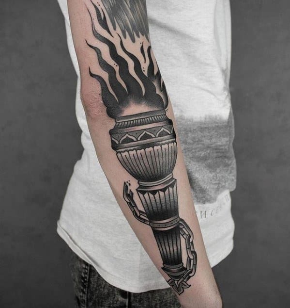 Large black and grey torch tattoo on the forearm with bold flames and a broken chain wrapped around the handle.