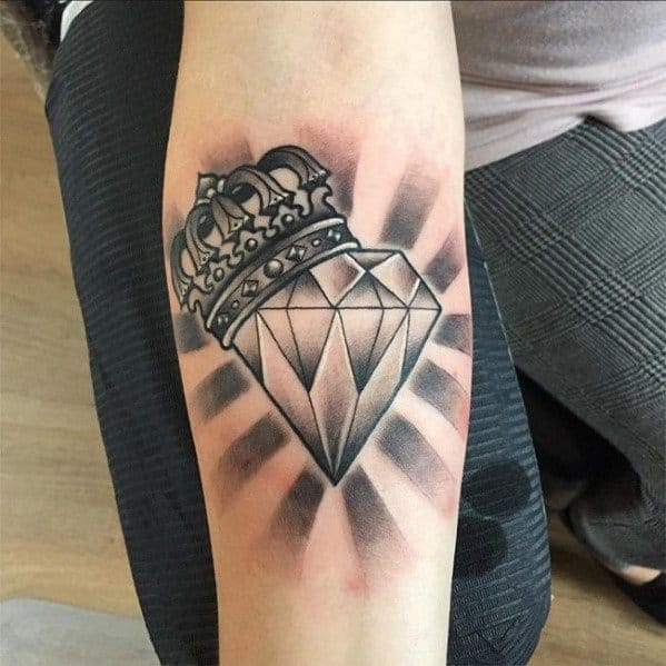 Black and grey forearm tattoo of a crowned diamond with radiant shading, combining regal and gemstone symbolism in bold style.