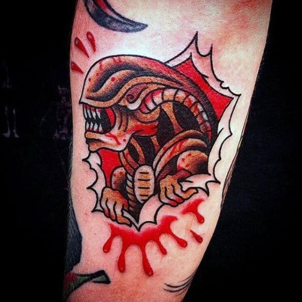 Neo-traditional Xenomorph tattoo with bold lines and red splatter, showing the alien bursting through the skin in a cartoonish style.