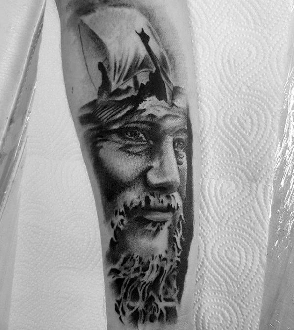 Black and white tattoo of a bearded man wearing a helmet with boat sails above his head