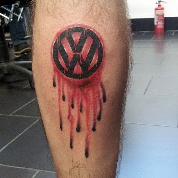 Bold black Volkswagen logo tattoo on the calf with red ink dripping effect, giving a raw and edgy appearance.