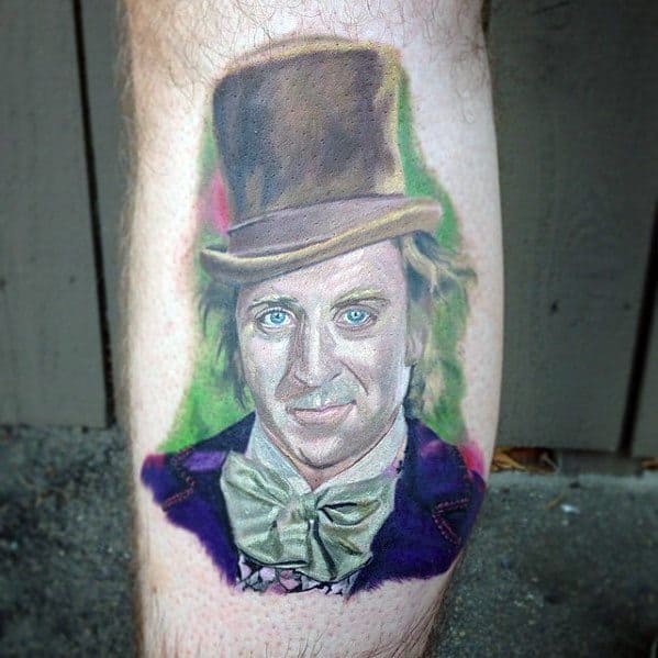 Realistic Willy Wonka tattoo featuring soft shading, a brown top hat, green bow tie, and a colorful background in pink and green hues.