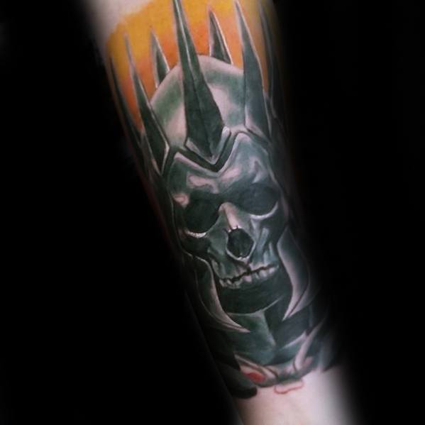Color Witcher tattoo of the Wild Hunt skull helmet with sharp black spikes and glowing orange background on the forearm.