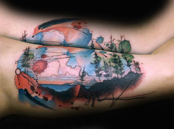 Abstract watercolor tattoo of a mountain landscape with trees, vibrant splashes of blue, red, and green, and dynamic brushstroke details.