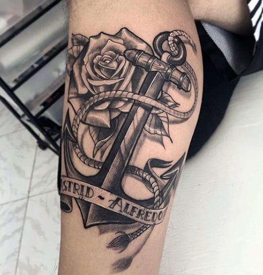 Anchor tattoo with a rose, rope, and names "ASTRID - ALFREDO" on a leg
