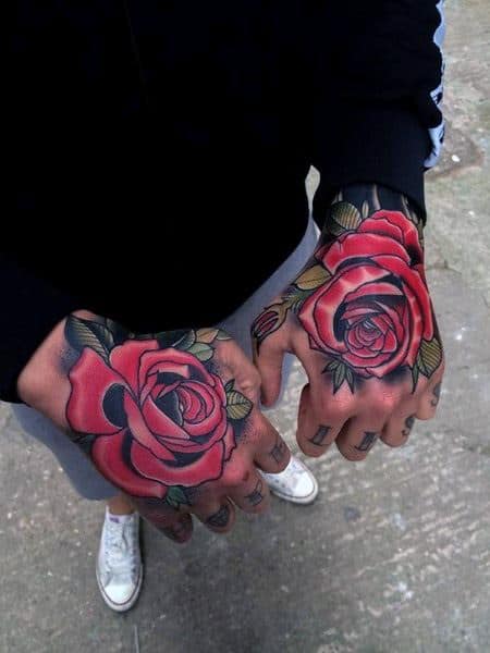 Two hands with vibrant red rose tattoos on the backs