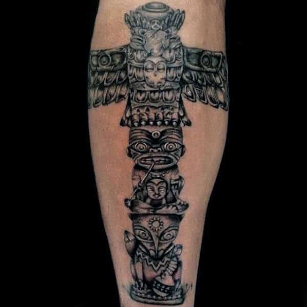 Male With Black Work Totem Pole And Peace Pipe Tattoo On Calf