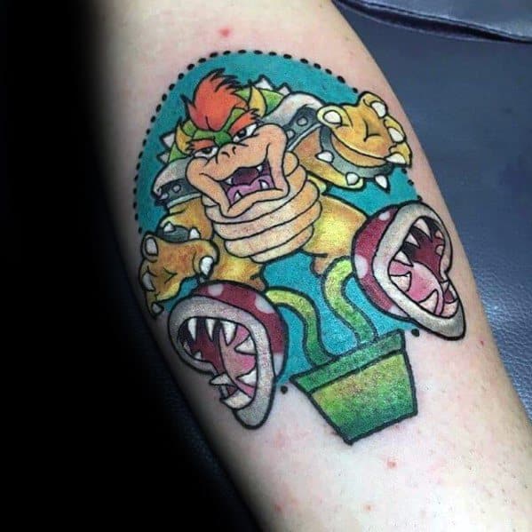 Vibrant Bowser tattoo on a man's arm featuring bold outlines, bright colors, and a dynamic design with Piranha Plants in a Mario-inspired theme.