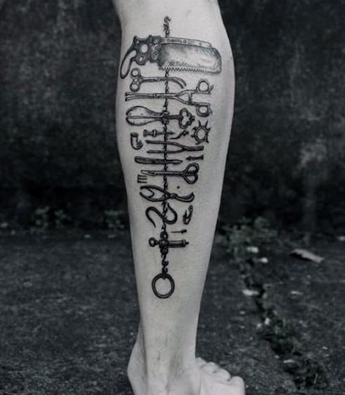 Black and grey calf tattoo of vintage surgical tools arranged vertically, featuring intricate shading for a realistic and eerie effect