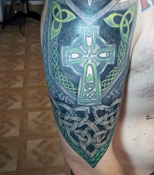 Tattooed arm featuring intricate Celtic cross and knot designs in green and gray