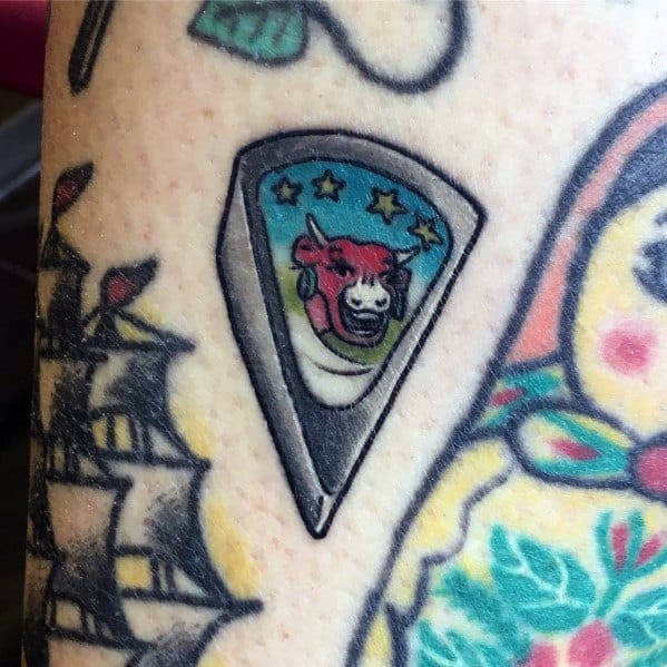 Colorful tattoo of a cheese wedge wrapper featuring a red cow logo with stars, resembling the iconic Laughing Cow packaging, with bold outlines and shading.