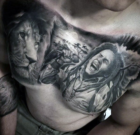 Black and gray chest tattoo of Bob Marley passionately singing, paired with a lion and scenic background symbolizing strength, freedom, and spirit.