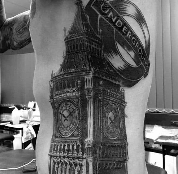 Detailed black and grey tattoo of Big Ben on the side of the torso, with the London Underground logo placed above the clock tower, creating a striking contrast and intricate shading.