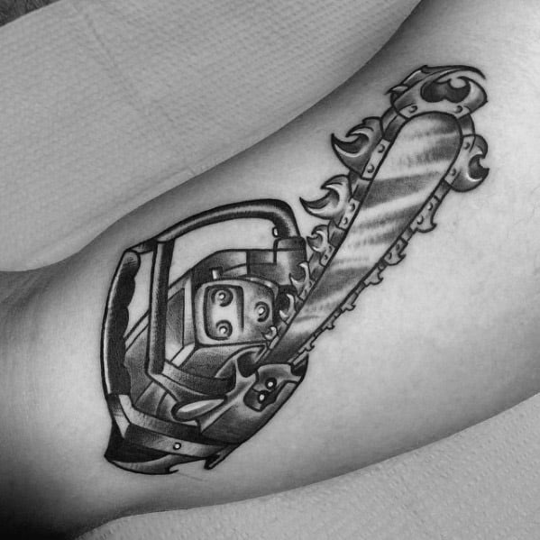 Black and gray chainsaw tattoo with stylized flames along the blade, combining realism with dynamic, fantasy-inspired design.