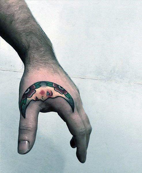 Side hand tattoo for men featuring a colorful crescent moon with floral details, curving from the thumb to the outer edge.