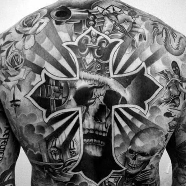 Back tattoo featuring a skull inside a cross with radiating beams, surrounded by religious, nautical, and skeletal elements in black and grey.