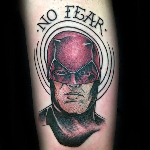 Daredevil tattoo with a bold black and red portrait, circular radar lines, and the words “No Fear” above symbolizing courage.